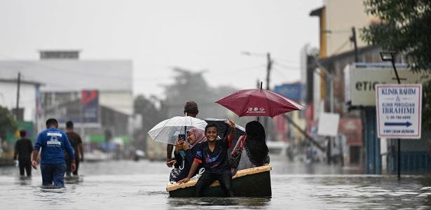 Pessoas usam barco para se locomover em rua na Malásia após fortes chuvas