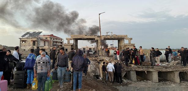 Pessoas se reúnem com seus pertences na fronteira do Líbano com a Síria