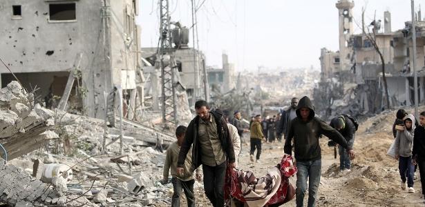 Homens palestinos carregam um corpo recuperado sob os escombros após seu retorno a Nuseirat, no centro da Faixa de Gaza em 29 de novembro de 2024