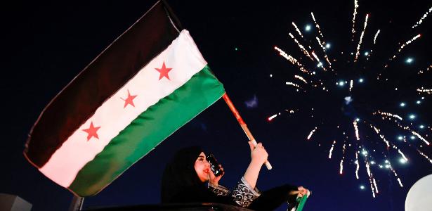 Mulher levanta nova bandeira síria durante manifestação em Damasco nesta sexta