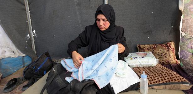 29.dez.2024 - Noura, a mãe do bebê palestino Jumaa Al-Batran, que morreu de hipotermia após viver em uma tenda com sua família deslocada, mostra seus pertences em sua tenda, em Deir Al-Balah, no centro da Faixa de Gaza