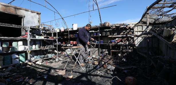 Um homem caminha por escombros de um comércio queimado após ataque de tropas israelenses na cidade de Qalqilya, na Cisjordânia, no último dia 21 de janeiro