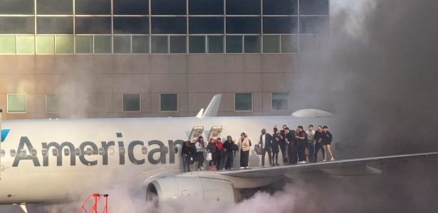 Passageiros em pé na asa de um avião da American Airlines enquanto são evacuados após o incêndio em um portão do Aeroporto Internacional de Denver, em Denver, Colorado, em 13 de março de 2025