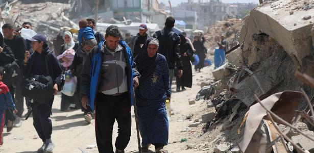 Palestinos caminham com seus pertences enquanto fogem de suas casas, após o exército israelense emitir ordens de evacuação, no bairro de Shujaiya, na Cidade de Gaza