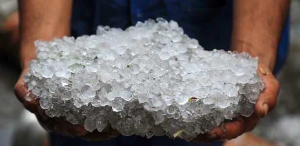 31.mai.2025 - Um membro dos serviços municipais de emergência mostra um bloco de granizo durante as obras de limpeza de uma passagem subterrânea obstruída após uma tempestade de vento atingir a cidade de Alexandria, no norte do Egito