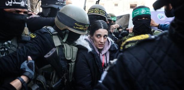 O grupo militante palestino Jihad Islâmica e combatentes do Hamas escoltam a refém israelense Arbel Yehud para entregá-la a uma equipe da Cruz Vermelha Khan Yunis em 30 de janeiro de 2025, como parte de sua terceira troca de reféns-prisioneiros