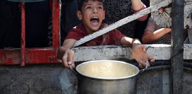 Um palestino reage enquanto espera para receber comida de uma cozinha de caridade, em meio a uma crise de fome, na Cidade de Gaza