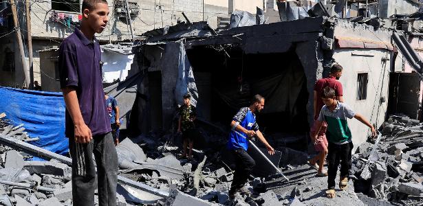 Palestinos em destroços de casa atingida por ataque de Israel a Deir Al-Balah, no centro de Gaza, ontem