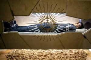 Santo Carlo Acutis in his tomb in Assisi wearing Nike Sneakers and North Sails sweatshirt