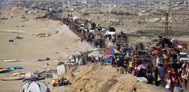 Palestinos deslocados seguem para o sul, em uma estrada na área do campo de refugiados de Nuseirat, no centro da Faixa de Gaza