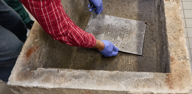 Arqueólogos removem a placa de chumbo da pedra fundamental aberta para examinar e documentar a descoberta em museu alemão