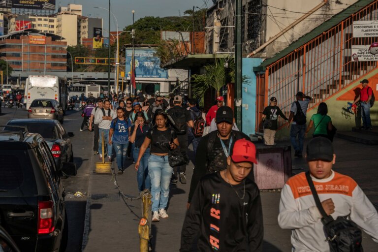 Pedestres em rua de Caracas; inflação faz venezuelanos comprarem menos alimentos (The New York Times)